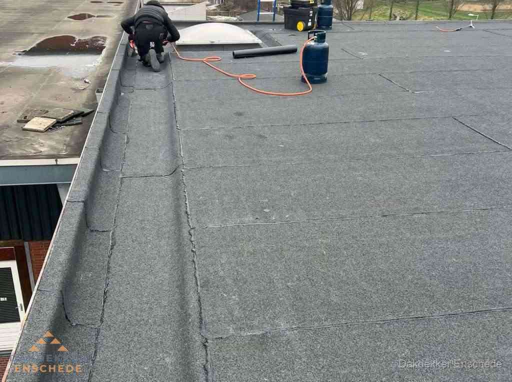 Dakdekker repareert bitumen dakbedekking op groot plat dak in Enschede Dakdekker repareert bitumen dakbedekking op groot plat dak in Enschede